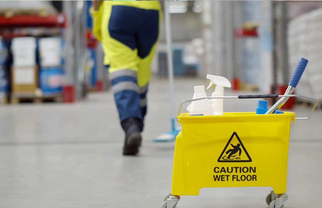 Cropped shot of janitor with bucket washing floor in warehouse